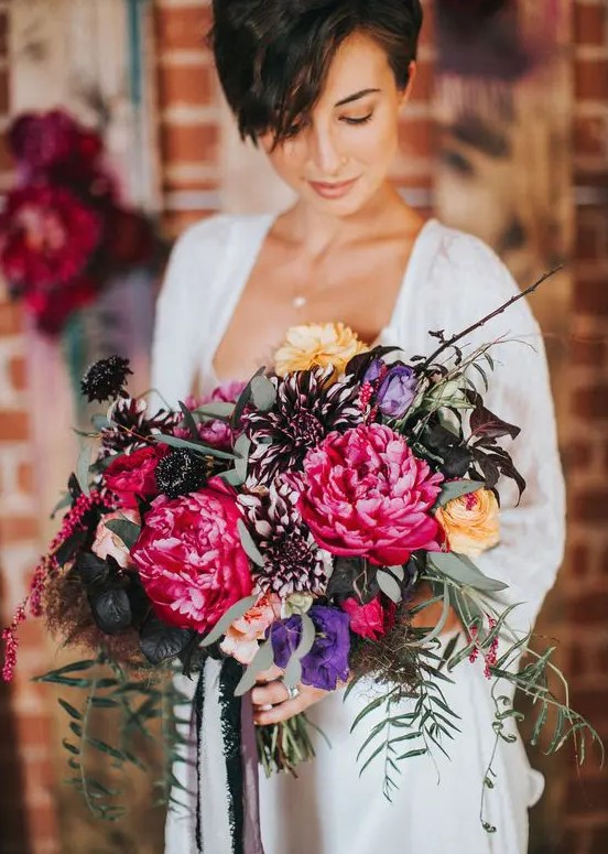a gorgeous jewel tone wedding bouquet with depe purple, purple, pink and yellow blooms and cascading greenery is a lovely idea for the fall