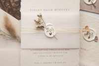 a gorgeous neutral textural paper invitation suite with a raw edge, a vellum cover with a dried flower wax seal