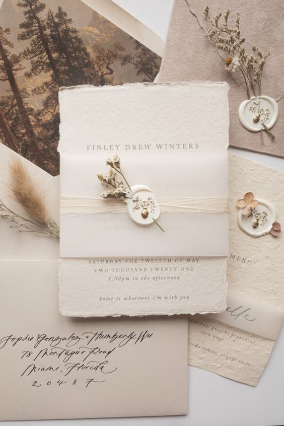 a gorgeous neutral textural paper invitation suite with a raw edge, a vellum cover with a dried flower wax seal