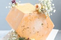 a hexagonal orange cake top forward wedding cake decorated with baby’s breath and some roses plus gold foil is amazing for an elegant art deco wedding