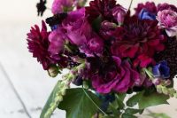 a jaw-dropping jewel tone wedding bouquet of burgundy, deep purple blooms, violet ones and greenery and berries for the fall