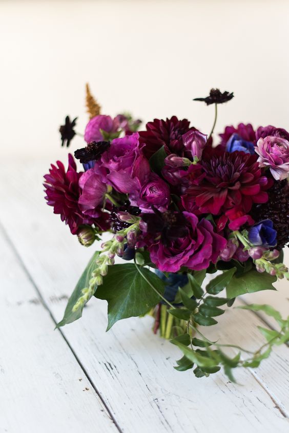 a jaw-dropping jewel tone wedding bouquet of burgundy, deep purple blooms, violet ones and greenery and berries for the fall