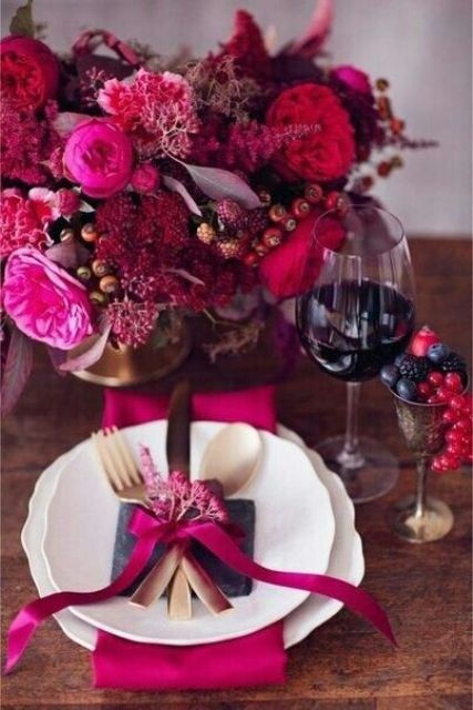 a jaw-dropping sumptuous wedding centerpiece with hot red, hot pink, purple blooms, various berries and no foliage is wow