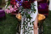 a jewel tone wedding bouquet with burgundy, purple, violet and pink blooms and cascading greenery for the fall