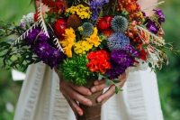 a jewel-tone wedding bouquet with yellow, red, purple flowers, allium, greenery, foliage for a cheerful wedding in summer or fall