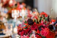 a jewel tone wedding centerpiece of deep red, burgundy and deep purple blooms and some greenery is very elegant