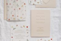 a lively summer wedding invitation suit in neutrals, with floral usual and vellum invites and beautiful beige envelopes