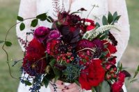 a lovely jewel tone wedding bouquet of purple, depe purple, burgundy, deep red blooms, greenery and privet berries is fantastic