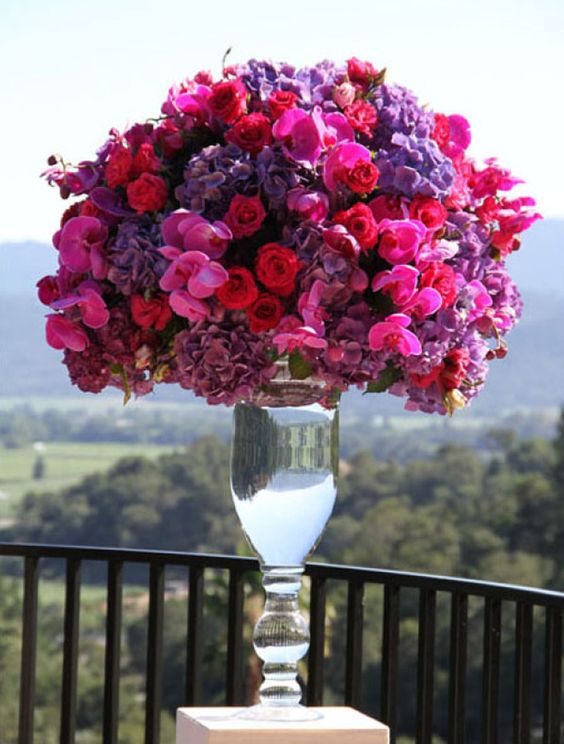 a luxurious tall wedding centerpiece done in jewel tones, with hot pink, deep red and violet blooms is a jaw dropping idea