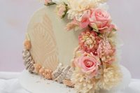a neutral cake top forward wedding cake decorated with sugar patterns and fresh ivory and pink blooms and greenery is great for spring or summer