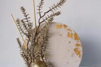 a pillowy pink buttercream cake with the frame of gold leaf around the edges and some whimsical branches and gold twigs for a modern and bold wedding