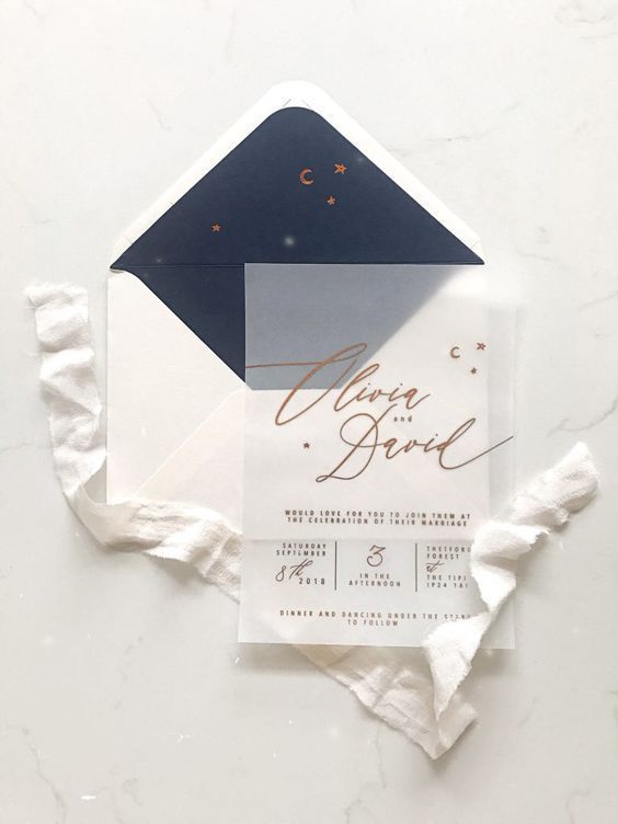 a pretty and delicate celestial wedding invitation suite with a white and navy envelope and a vellum invitation with gold calligraphy