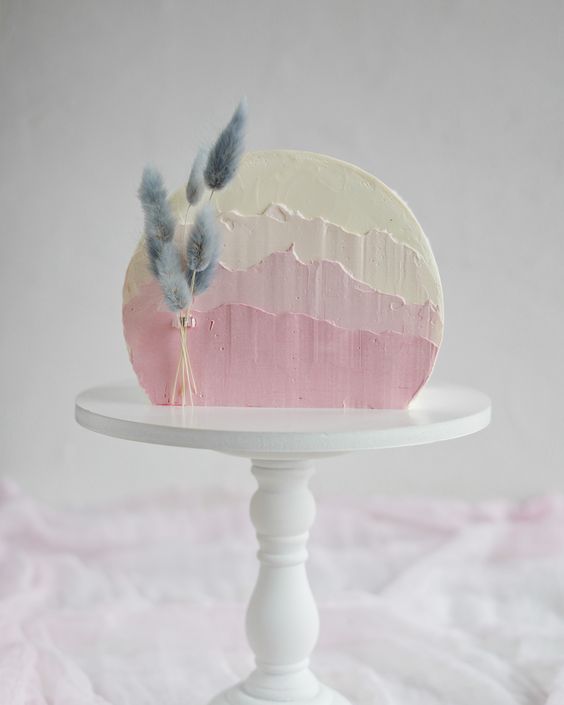 a pretty ombre pink wedding cake with textural buttercream and some lilac bunny tails for a spring or pastel summer wedding