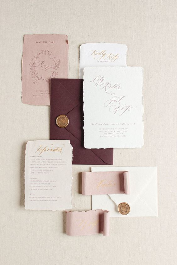 a pretty wedding invitation suite with dusty pink, deep purple and neutral parts, calligraphy and gold seals
