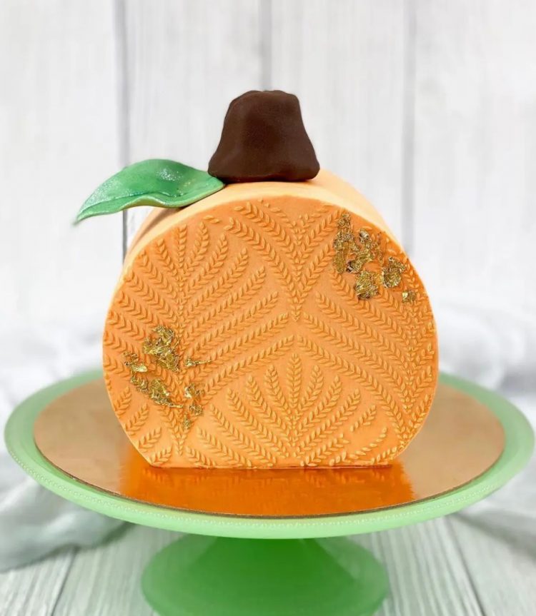 a pumpkin-inspired seasonal cake top forward wedding cake topped with a leaf, a candy, some patterns and a chocolate candy on top for a fall wedding