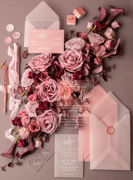 a romantic pink wedding invitation suite with vellum invites, envelopes, clear acrylic invites and pink envelopes is wow