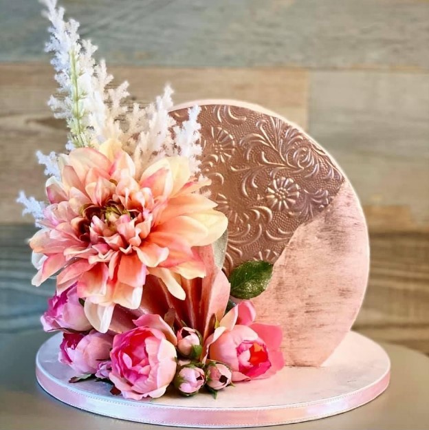 a stunning two tone arch wedding cake with pink and peachy pink blooms and dried grasses for a bright summer wedding