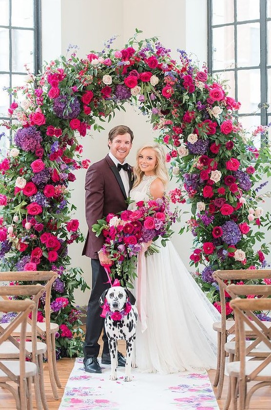 a super bold and breathtaking floral wedding arch with purple, pink, fuchsia, burgundy, blush blooms and textural greenery for a statement