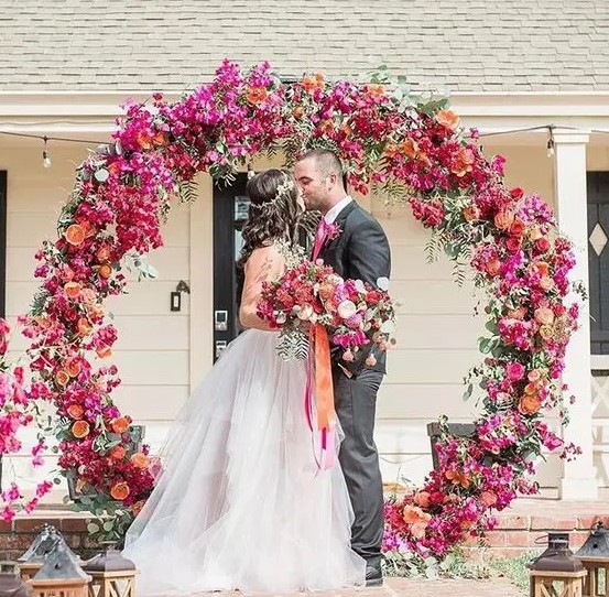 a super bold circle wedding arch with fuchsia, pink, orange blooms and citrus for a southern wedding