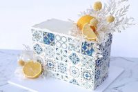 an Amalfi coat inspired rectangle wedding cake with azulejo blue tiles printed, lemons, white dried grasses and billy balls for an Italian wedding
