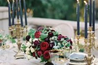 an elegant moody wedding centerpiece of white, ruby red and plum-colored blooms and greenery