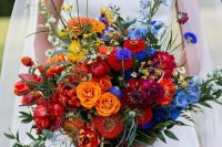 an extra bold wedding bouquet with burgundy and hot red blooms, orange and yellow ones, purple and blue, greenery is amazing for the fall