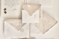 an organic handmade paper wedding invitation suite with asymmetrical paper and envelopes, with calligraphy and modern lettering
