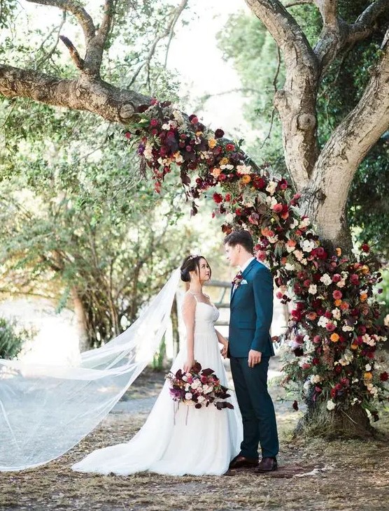 burgundy, red and orange flower tree decor to use as a wedding backdrop - living tree decor is a very trendy idea