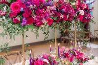 tall jewel-tone centerpieces with hot pink, purple and violet blooms and greenery and matching table runners and purple candles