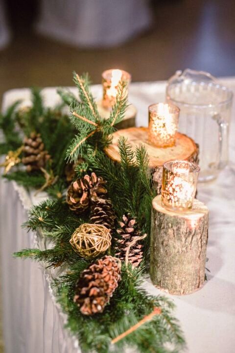 a beautiful and easy to DIY winter wedding centerpiece of evergreens, pinecones, gilded twine balls, tree stumps with candleholders