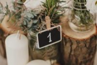 03 a beautiful cluster wedding centerpiece of tree stumps, white blooms and herbs, a chalkboard number and pillar candles