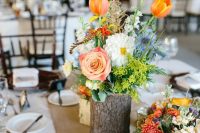 04 a colorful rustic wedding centerpiece of a tree stump with bold blooms and greenery and candles around is a lovely idea for a rustic wedding