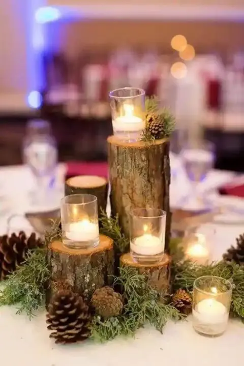 a lovely forest wedding centerpiece of tree stumps and branches, with moss, pinecones and candles is a cool idea to realize yourself