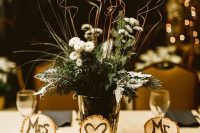 09 a rustic winter wedding centerpiece of evergreens, white blooms and twigs, cut tree stumps with monograms and evergreens
