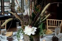 10 a woodland wedding centerpiece of a moss, pinecones, a tree stump with greenery, blooms, grasses and some candles around is all cool