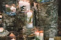 16 a woodland or rustic wedding altar made of tree stumps and candles in glasses, with moss and greenery for a rustic wedding