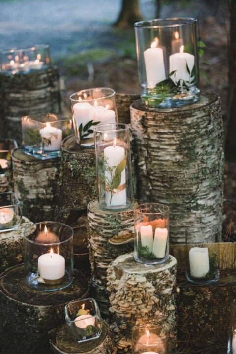 a woodland or rustic wedding altar made of tree stumps and candles in glasses, with moss and greenery for a rustic wedding
