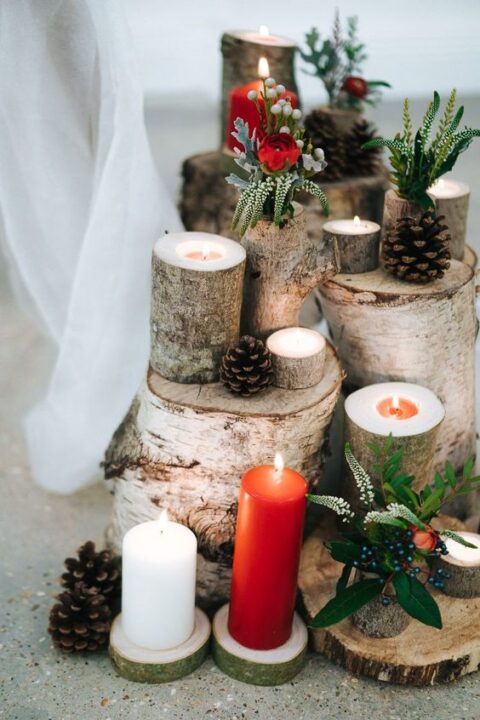 a fabulous Christmas wedding decoration made of tree stumps and branches, pinecones, red and white candles, berries and greenery, some red blooms
