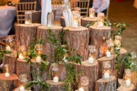 20 a large rustic wedding decoration made of tree stumps with greenery and candle lanterns is a cool idea to rock