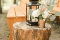 21 a large tree stump with a candle lantern and a neutral floral arrangement with greenery is a great idea for a rustic wedding