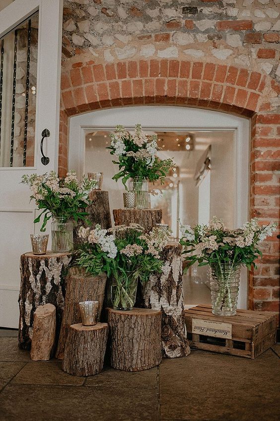 a pretty rustic wedding decoration made of tree stumps with wildflower and greenery arrangements and candles is a lovely idea