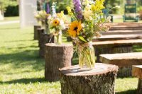 24 a rustic wedding aisle styled with tree stumps and bold floral arrangements is a stylish idea for a rustic or boho wedding