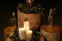 27 a rustic wedding decoration of tree stumps with greenery, candles and bottles is a great idea for a rustic or woodland wedding
