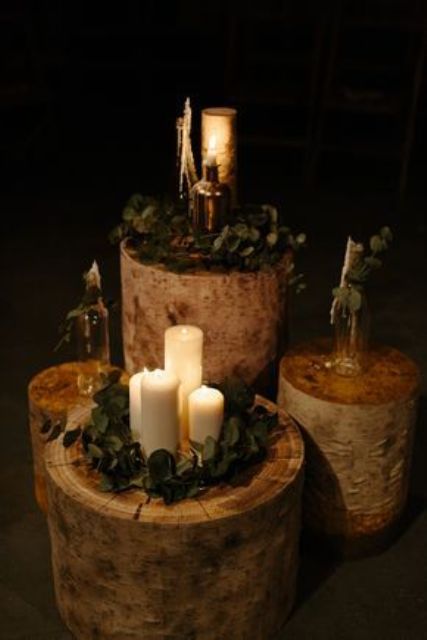 a rustic wedding decoration of tree stumps with greenery, candles and bottles is a great idea for a rustic or woodland wedding