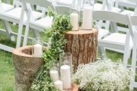 28 a rustic wedding decoration of tree stumps, greenery and candles plus a bucket with baby’s breath is a cool piece to DIY for a wedding