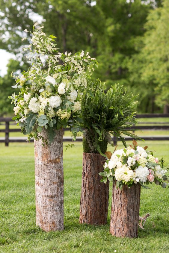 a wedding decoration of tree stumps, white blooms and greenery is a cool rustic idea for a wedding, make one yourself