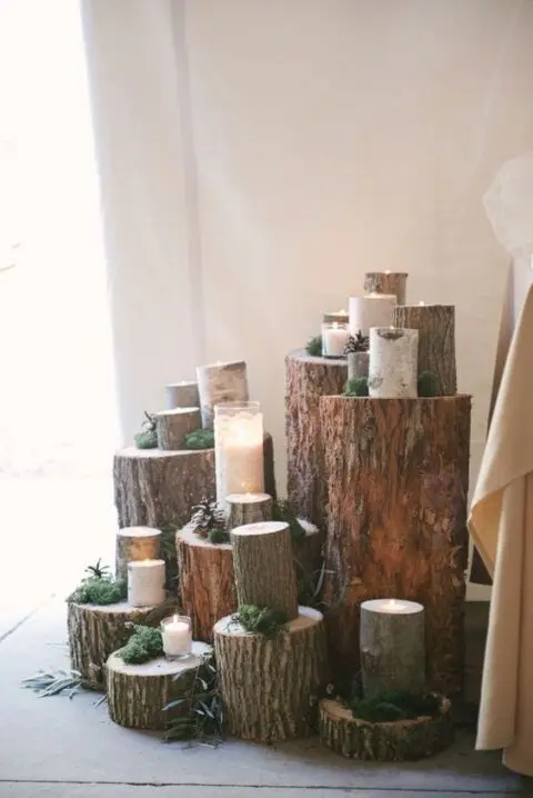 rustic wedding decor composed of tree stumps with moss, pinecones and candles plus greenery is a great idea for a rustic or woodland wedding