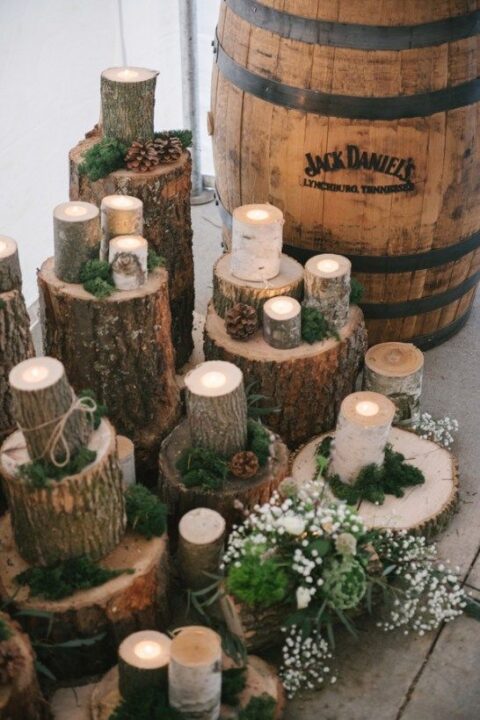 woodland-themed wedding decor with lots of tree stumps and cut tree branches as candleholders, moss, evergreens and pinecones