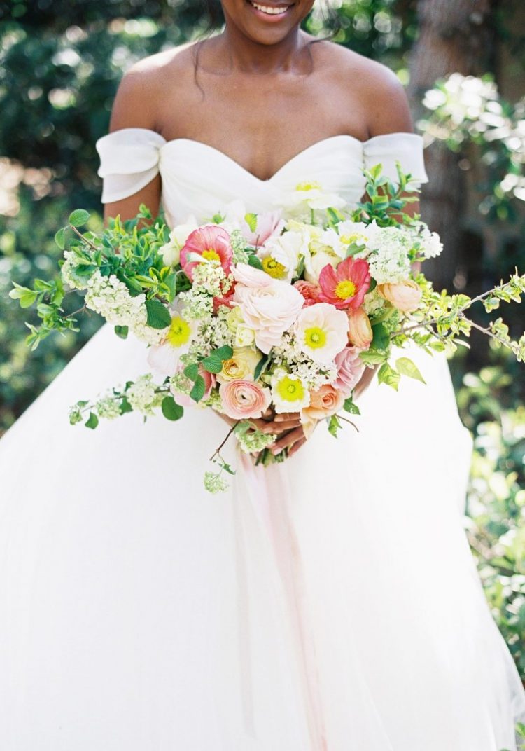 a beautiful and dimensional wedding bouquet of red poppies, blush and yellow ranuculus, white blooms and greenery is amazing for a spring or summer bride
