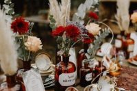 a boho cluster wedding centerpiece of apothecary bottles with neutral and burgundy blooms, eucalyptus and pampas grass is amazing